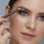 Woman shaping eyebrow with brow pencil closeup